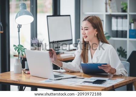 Asian woman sitting at a desk working in the office use a computer, laptop Royalty-Free Stock Photo #2093972188
