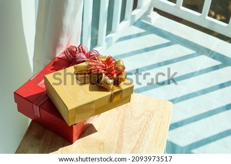 Red and gold gift box on wooden table.
