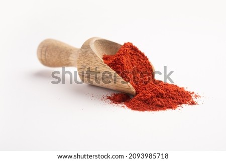 Red chilli powder in a wooden measuring scoop or spoon on a white background Royalty-Free Stock Photo #2093985718