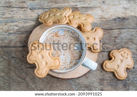 Christmas cookies, Cappuccino or Latte coffee and gingerbread man cookies on wooden table for noel or new year. Man shaped noel biscuits 