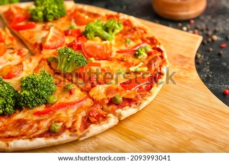 Board with tasty vegetarian pizza on dark background, closeup