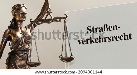 Symbol image: Reference book traffic law and a Justitia with the german title Straßenverkehrsrecht (Traffic Law)