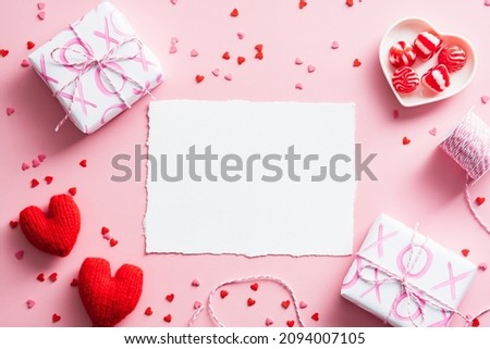 Happy Valentines Day composition. Flat lay blank paper card, gift boxes, red hearts on pastel pink background.