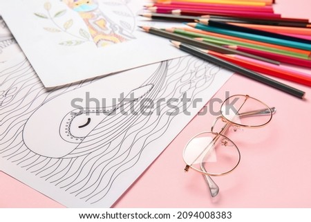 Coloring pictures, markers and pencils on table