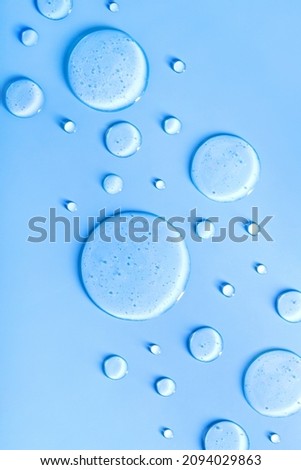  round drops of transparent gel serum on blue background with place for text Royalty-Free Stock Photo #2094029863