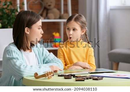 Speech therapist working with cute girl in clinic Royalty-Free Stock Photo #2094038110