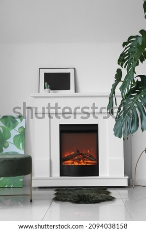 Stylish interior of living room with fireplace and tropical plant in pot