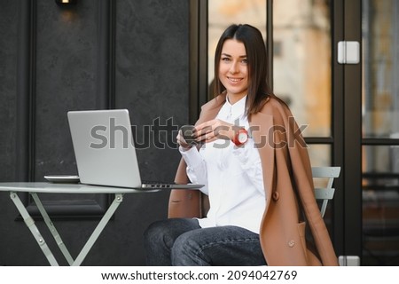 Photo portrait of gorgeous attractive woman working on laptop typing sitting in cafe drinking coffee