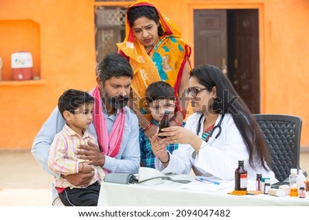 Young Indian Female Doctor with rural family give medicine outdoor village hospital,Healthcare government camp concept. Parents with two son getting medical help and support by pediatrician Royalty-Free Stock Photo #2094047482
