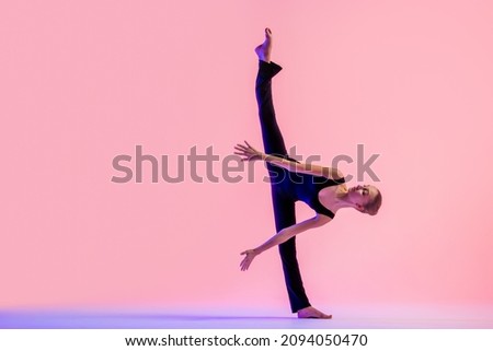 Young teenager dancer dancing on red studio background. Ballet, dance, art, modernity, choreography concept