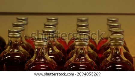 Top parts of arrayed bottles with caps, filled with some red liquid. Shallow focus.
