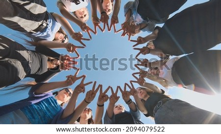 A group of girls makes a circle from their fingers.