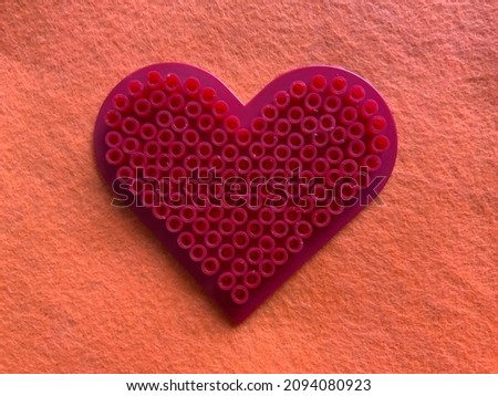 Red heart made of fuse beads with an orange background (perler beads)