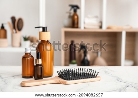 Hair brush and bottles of cosmetic products on table in room Royalty-Free Stock Photo #2094082657