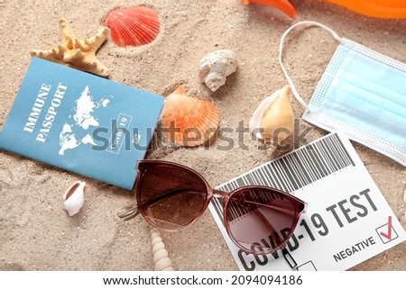 Immune passport, covid-19 test result, sunglasses and medical mask on beach