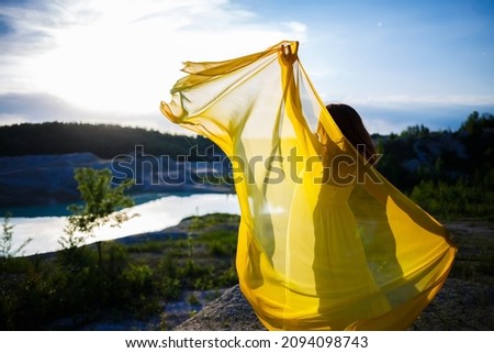 Summer lifestyle of stunning happy woman running in nature. In a long yellow dress. Romantic mood. Enjoying the sunshine. Sunny day. Selective focus