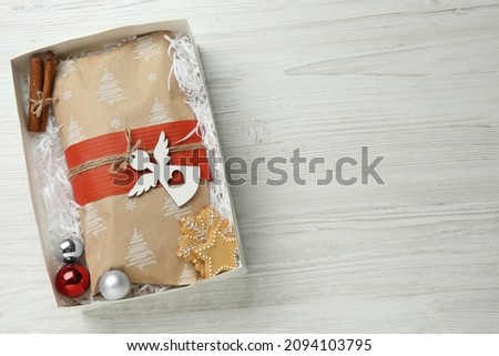 Wrapped Christmas Stollen and decoration in box on white wooden table, top view. Space for text