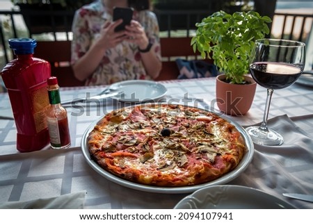 Delicious italian pizza, tabasco and wine, Woman taking pictures on smartphone