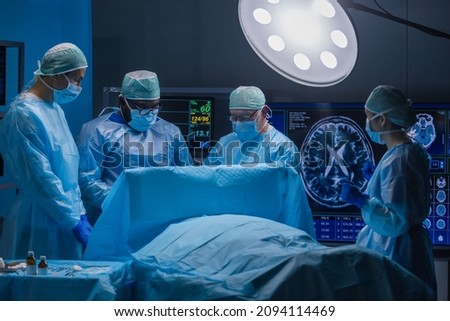 Multiracial team of professional medical surgeons performs the surgical operation in a modern hospital. Doctors are working to save the patient. Medicine, health and neurosurgery. Royalty-Free Stock Photo #2094114469