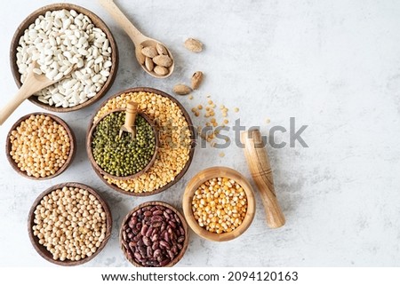 Various dried legumes in wooden bowls top view flat lay on white marble background with copy space Royalty-Free Stock Photo #2094120163
