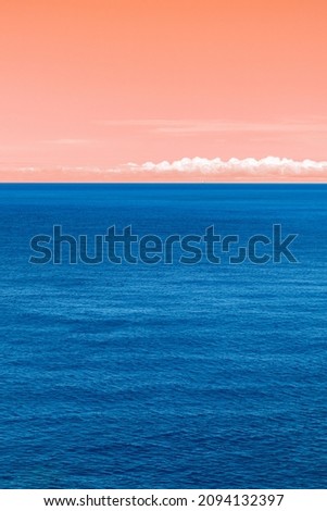 Artistic colored blue Ionian sea and orange sky vertical view in Greece. Bright day with scenic white clouds over rippled deep blue water surface