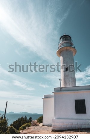 Ionian sea island lighthouse white building on a bright clear blue day in Greece. Scenic travel destination. Lefkada island. Vertical, color graded