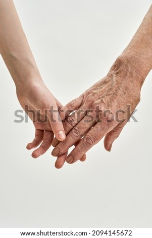 Cropped image of senior grandmother and young granddaughter holding hands each other. Age and generation concept. Family relationship, affection, join, unity. White background in studio. Copy space Royalty-Free Stock Photo #2094145672