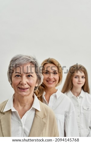 Row of serious caucasian family of three female generations looking at camera. Age and generation concept. Grandmother, mother and granddaughter. Isolated on white background in studio. Copy space Royalty-Free Stock Photo #2094145768