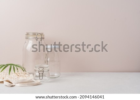 Set of glass jars and bags for zero waste grocery shopping. Eco friendly and reuse concept. Side view, light beige background