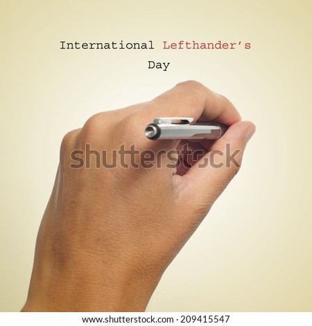 a man left-hand with a pen and the sentence International Lefthanders Day on a beige background Royalty-Free Stock Photo #209415547