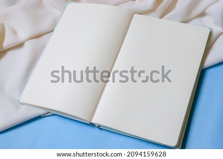 Stationery for graphic designer portfolio. Top view, dotted notebook, blue background, paper and light fabric. Responsive mockup and adaptive colors