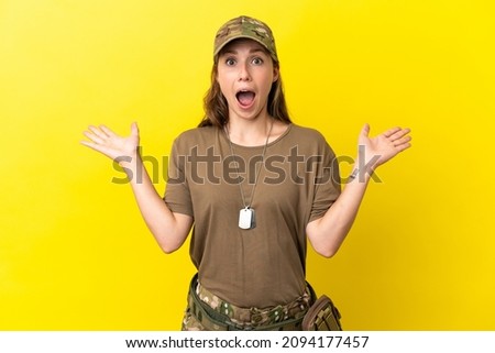 Military caucasian woman with dog tag isolated on yellow background with shocked facial expression