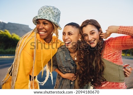 Three female friends smiling while embracing each other. Female youngsters having fun while standing together outdoors. Group of generation z friends making happy memories together. Royalty-Free Stock Photo #2094180670