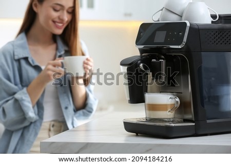 Young woman enjoying fresh aromatic coffee in kitchen, focus on modern machine Royalty-Free Stock Photo #2094184216