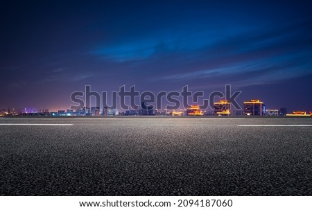 The night view of the city in front of the asphalt road