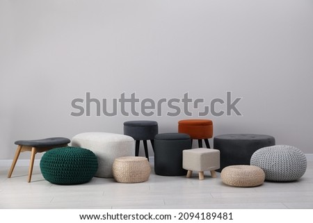 Different stylish poufs and ottomans near light grey wall Royalty-Free Stock Photo #2094189481