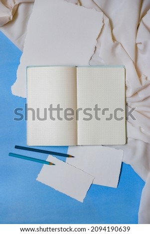 Stationery for graphic designer portfolio. Top view, dotted notebook, blue background, watercolor paper and light fabric. Responsive mockup and adaptive colors