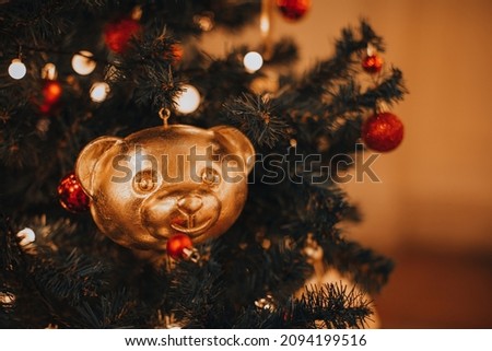 Golden festive Christmas toy figurine of teddy bear head hanging on Christmas tree. Creative Christmas decor. Winter holiday and New Year details