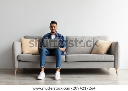 Remote Work. Handsome Middle Eastern Freelancer Guy Working With Laptop At Home, Arab Millennial Man Sitting On Couch In Living Room And Using Computer, Enjoying Distance Job Opportunities, Copy Space Royalty-Free Stock Photo #2094217264