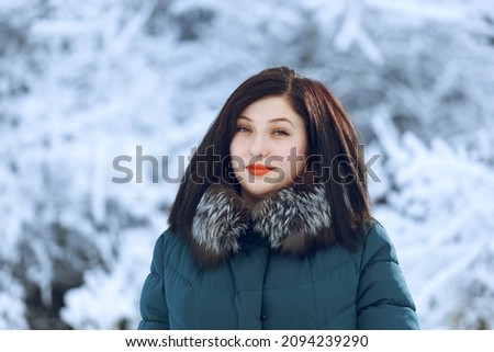 Portrait of a beautiful smiling young woman in a green jacket in the winter outdoors. Winter concept. Photo of a girl who is not a model