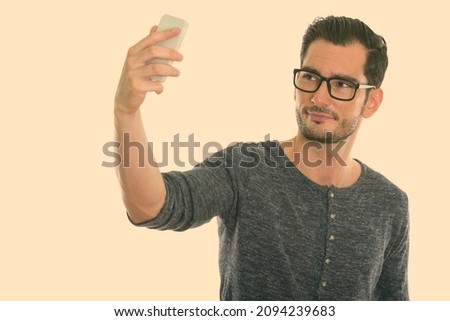 Studio shot of young handsome bearded man isolated against white background