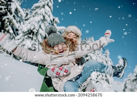 Mother and daughter play in beautiful winterlandcape and the mother carries the child through the air.