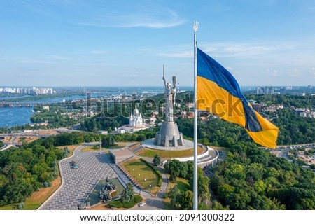 Aerial view of the Ukrainian flag waving in the wind against the city of Kyiv, Ukraine near the famous statue of Motherland. Royalty-Free Stock Photo #2094300322