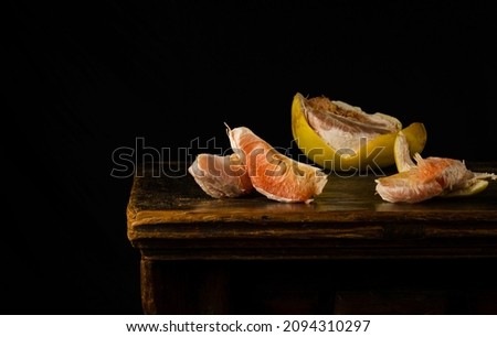 Still life of peeled grapefruit on wooden table against black background