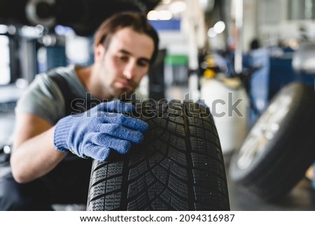 MOT. Vehicle inspection. Caucasian male young car technician mechanic changing repairing fixing wheel tire of automobile at service station Royalty-Free Stock Photo #2094316987