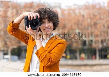 Young brunette woman with curly hair taking a picture looking at the camera