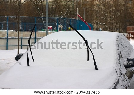raised windshield wipers on a snow-covered car