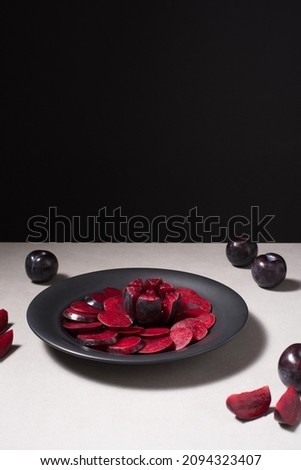 Sliced ​​black plums in a black plate on a gray table