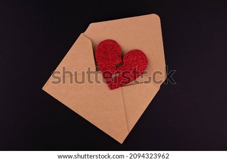 Kraft brown envelope with a broken red heart on a black background.