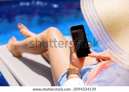 Woman using mobile phone while relaxing by the pool